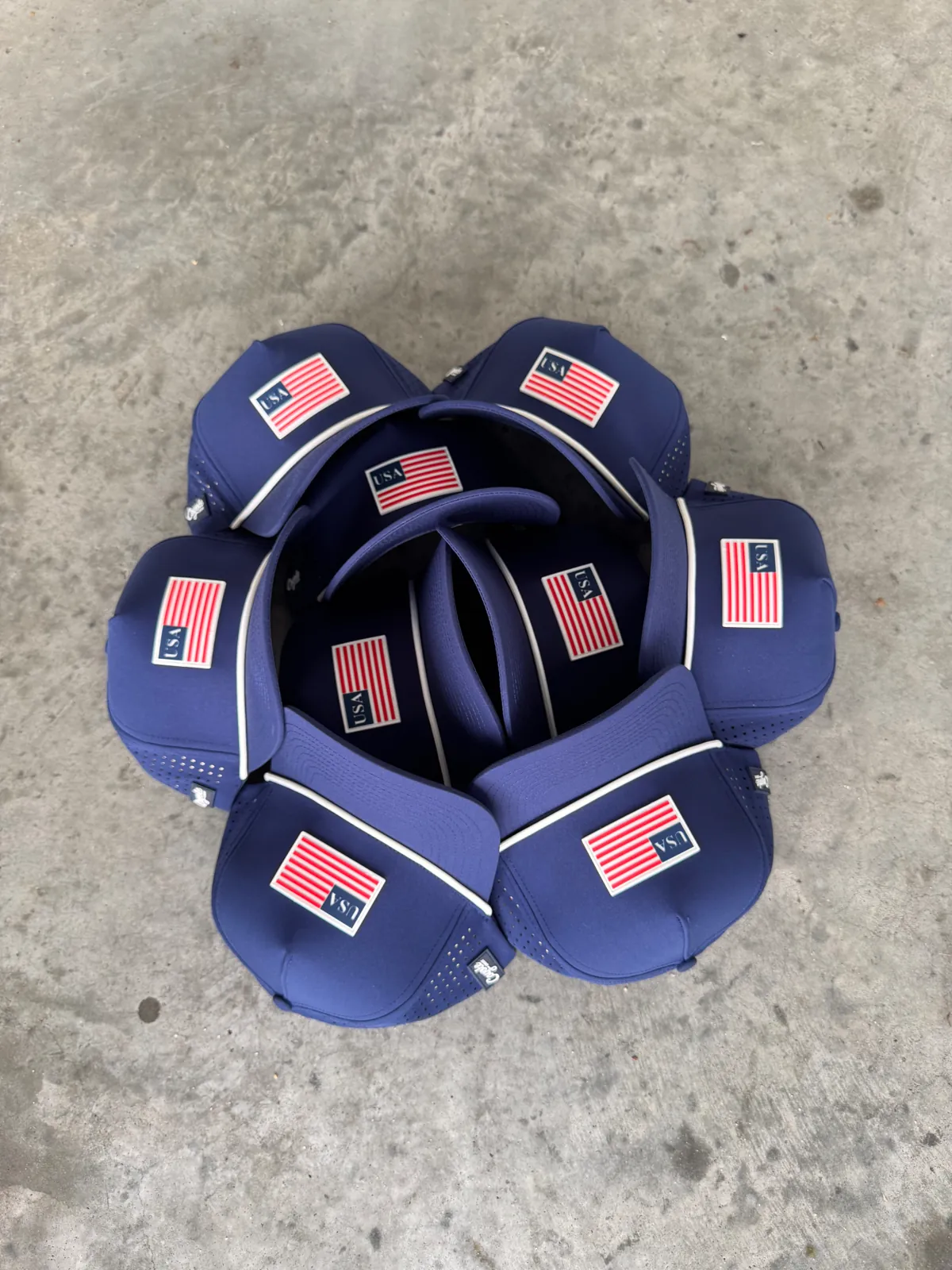 Navy USA flag tournament hats arranged on concrete