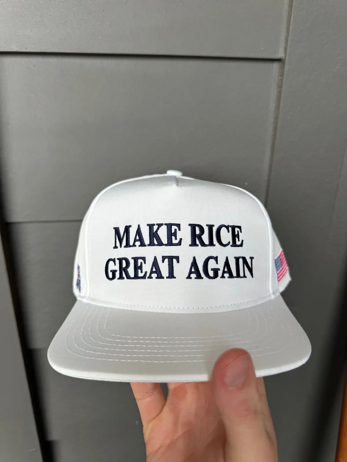 White five-panel hat with navy front embroidery and side flag detail