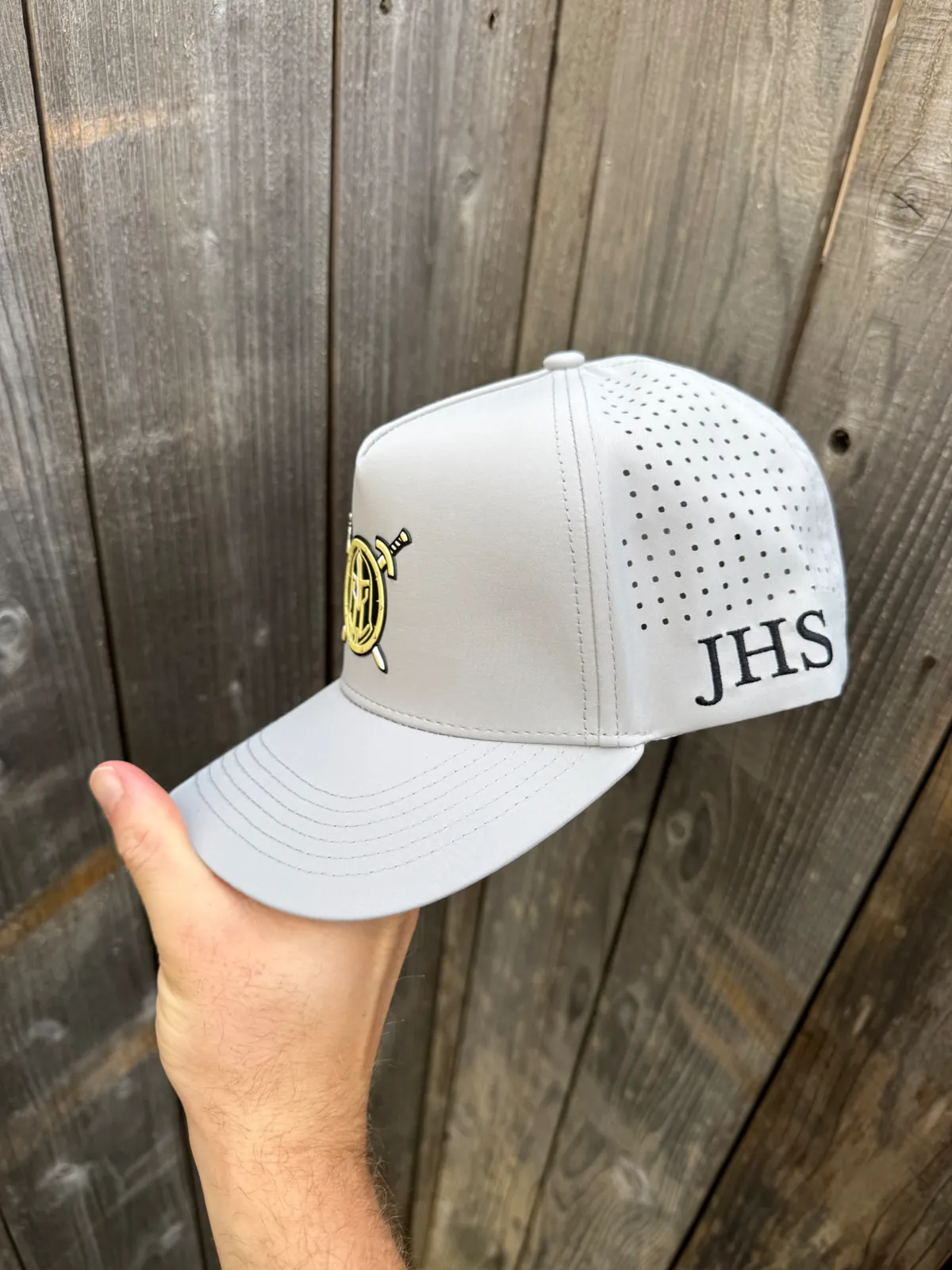 Gray performance hat with a gold rubber heat press shield patch and JHS side embroidery