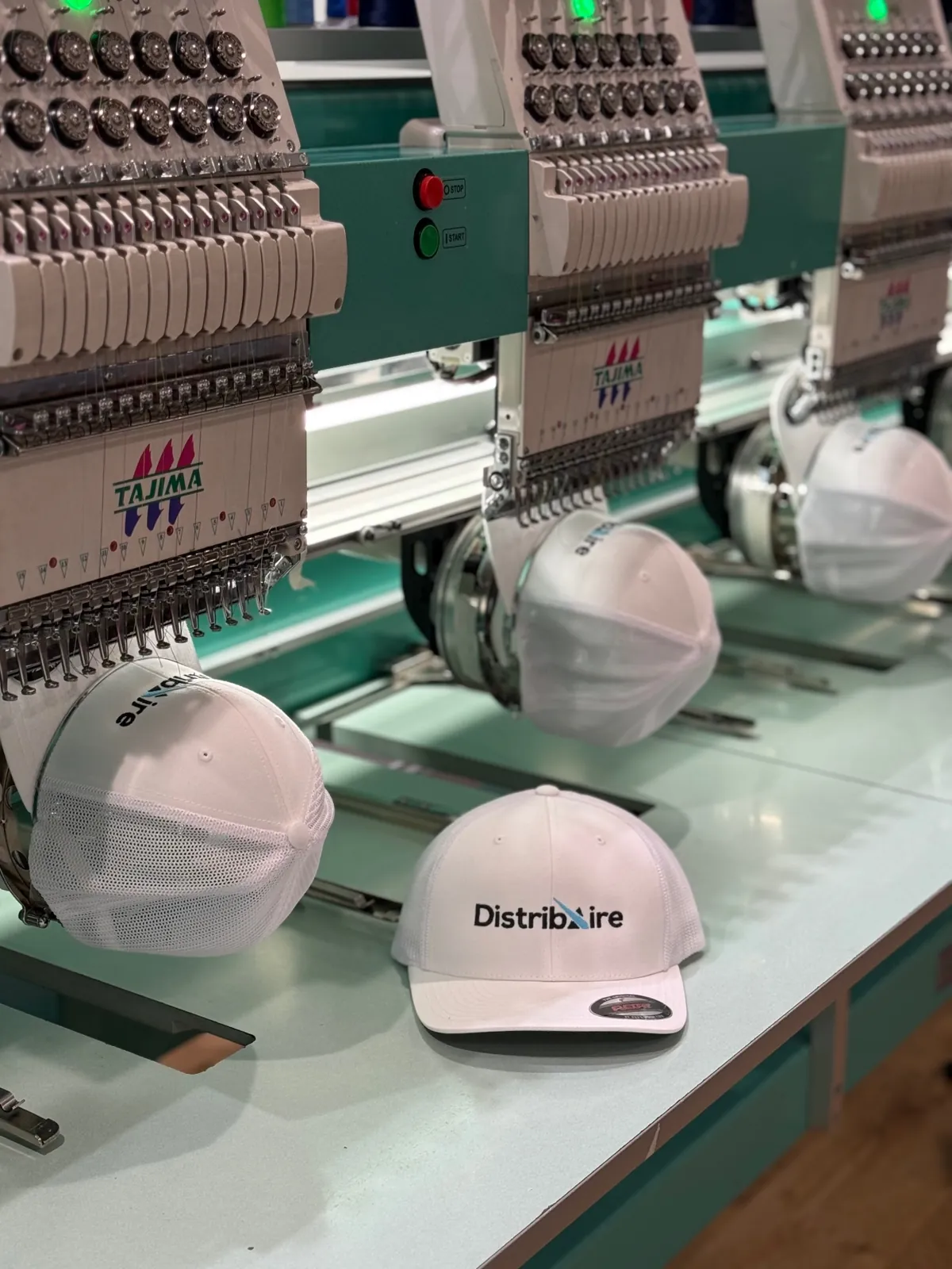 White corporate hats being embroidered on commercial machines