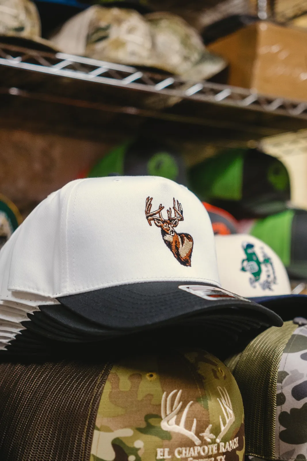 Embroidered deer hat displayed among finished hats in production