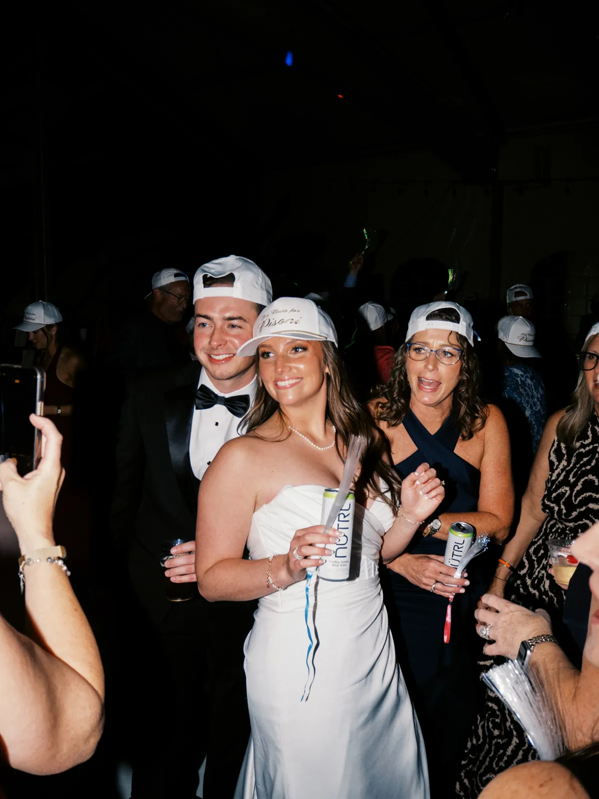 Wedding guests wearing white custom embroidered hats at an evening reception